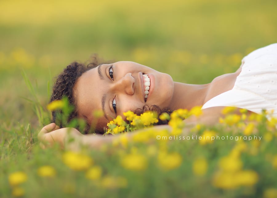 Girl laying in a field of yellow flowers