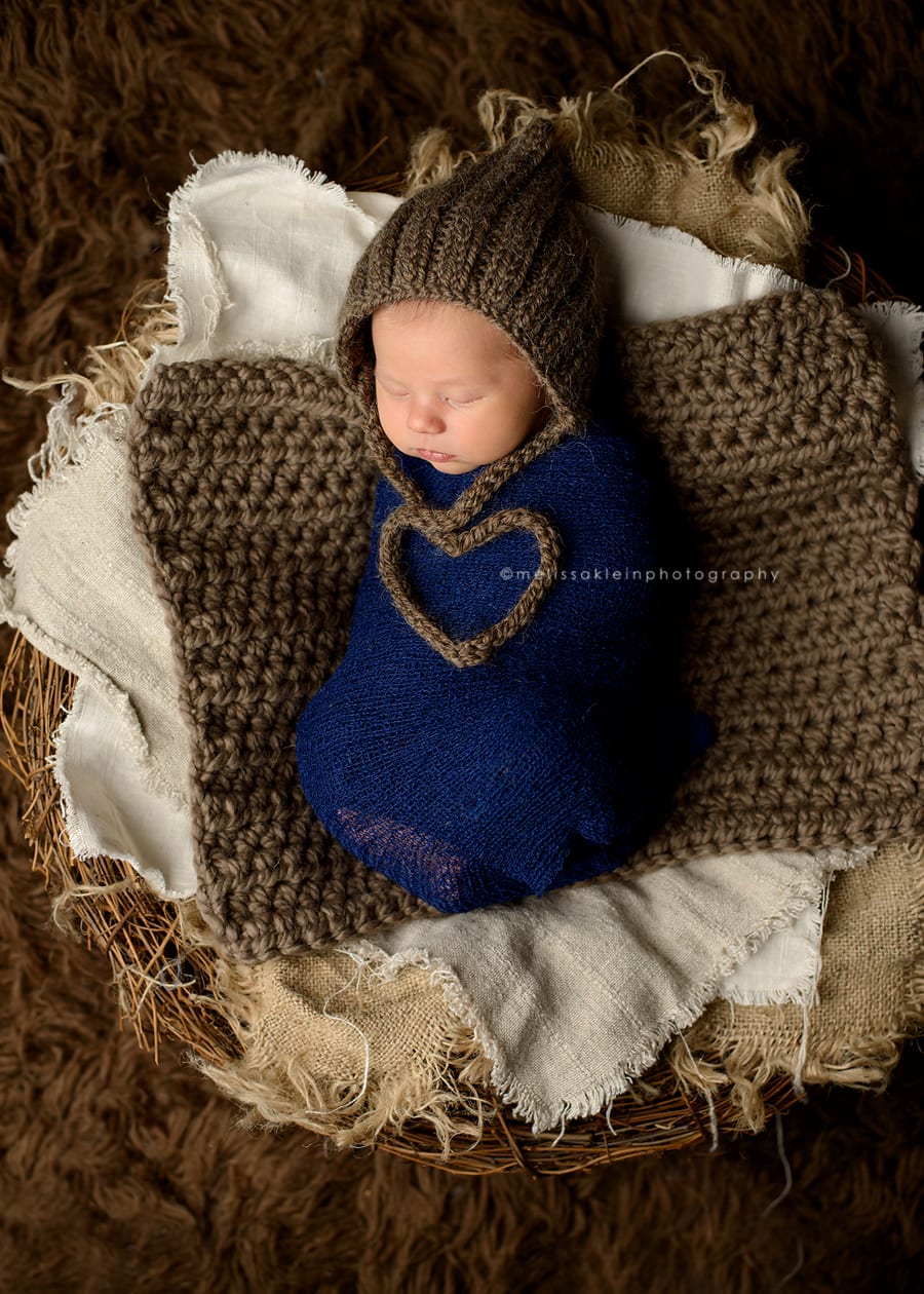 newborn baby with strings tied in a heart shape