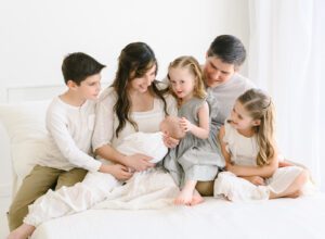 newborn photo of family of six on white bed