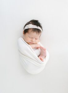 newborn baby girl with lots of hair on white backdrop