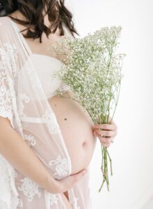 pregnancy photo with baby's breath flowers and lace robe