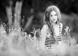 black and white portrait of girl sitting in a field, model