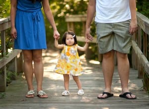 baby outdoors holding parents hands