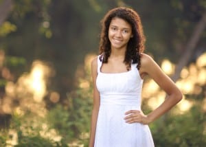high school girl standing by backlit lake with bokeh