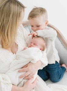 Newborn photo with toddler brother gently touching forehead