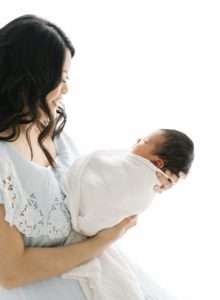 backlit photos of mom proudly holding newborn baby boy
