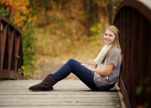 Girl sitting on bridge with fall colors
