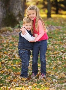 siblings hugging in fall leaves