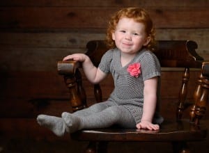 girl in chair with wood backdrop