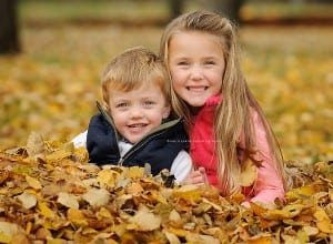 children sitting in a big pile of leaves