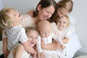 mom and five kids on bed in studio with Minneapolis newborn photographer