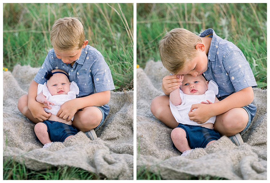 Big Brother snuggles with baby sister in the grass