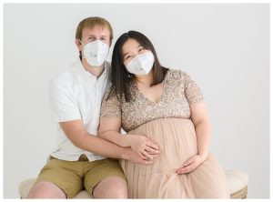 maternity photo of mom and dad wearing masks