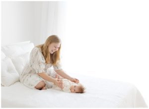 natural light photo of mom and 3 month old baby girl playing on bed