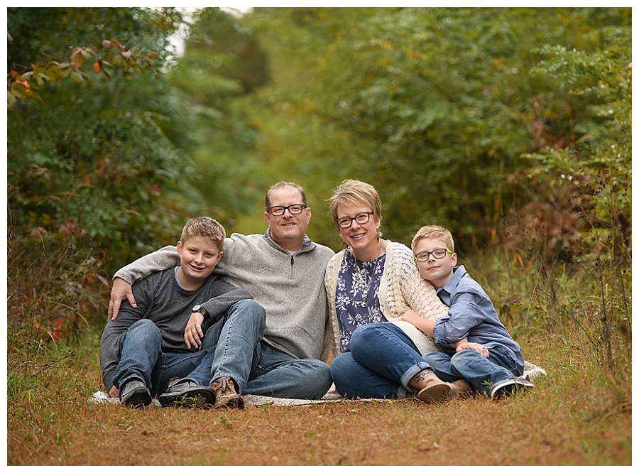 family with pre-teens sitting for fall outdoor photos