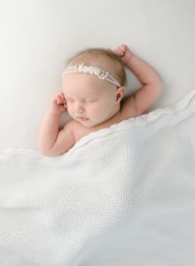 sleeping newborn baby girl on white blanket
