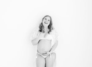 black and white photos of pregnancy woman in white lace robe laughing