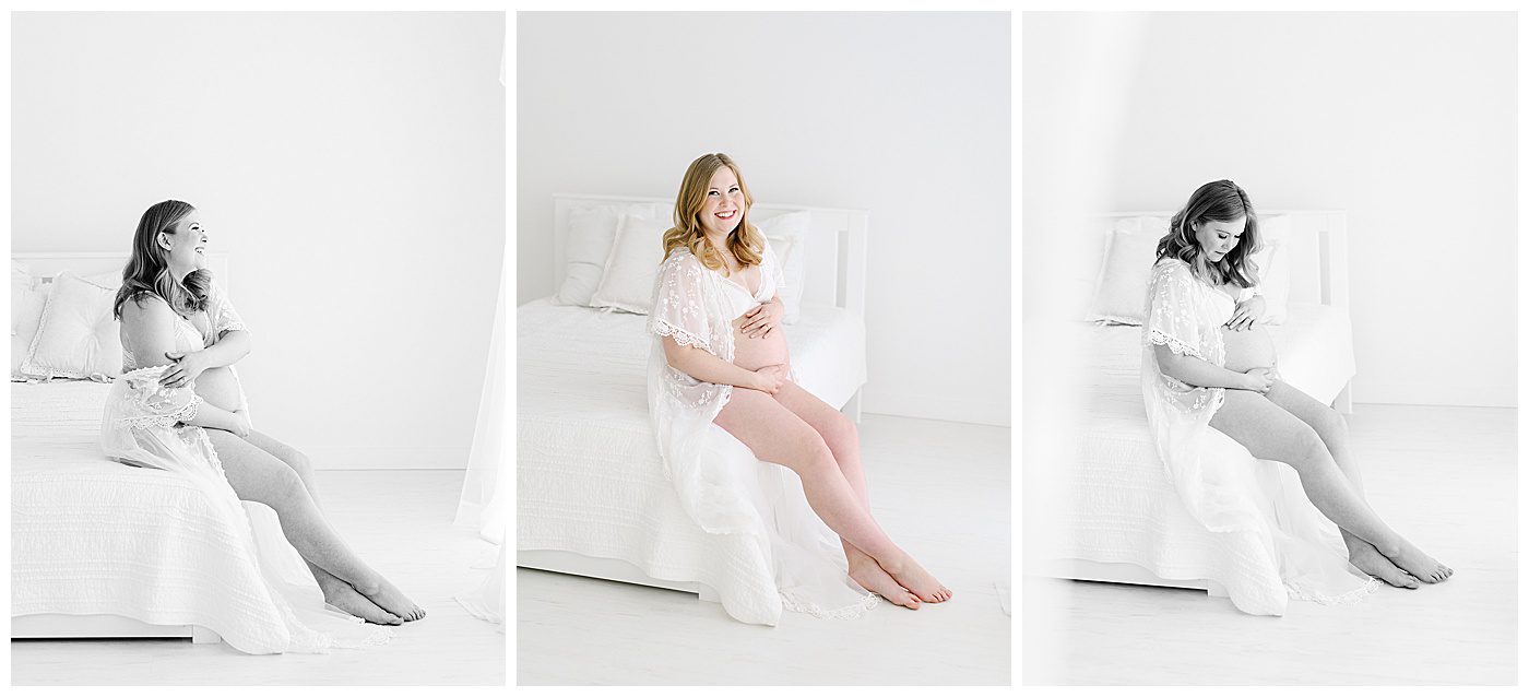 boudoir maternity photographer photographs woman in white lace robe on bed in natural light studio.