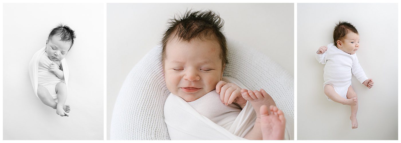 Smiling newborn baby boy in white onesie on white blanket