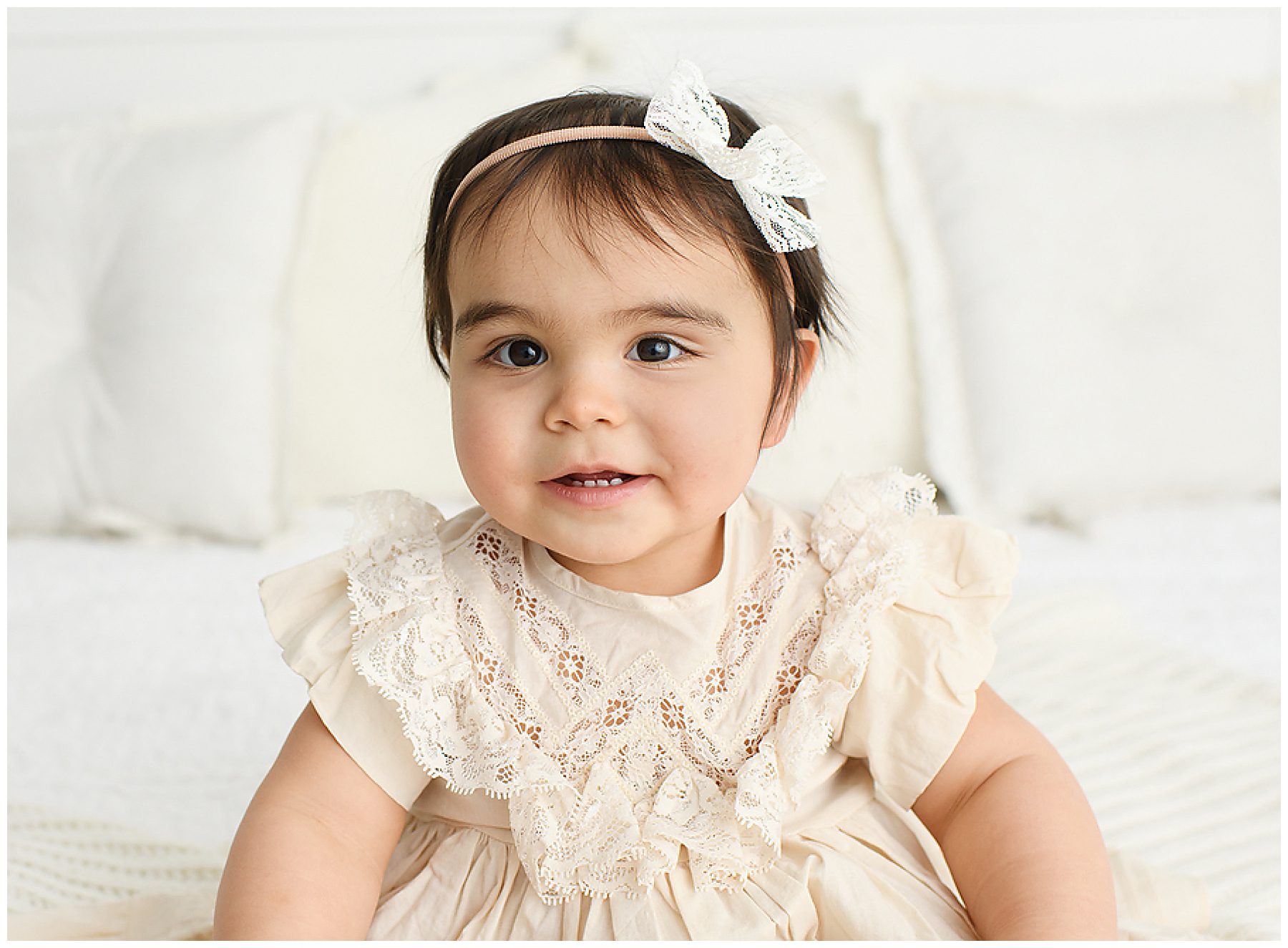 one year old baby girl in cream colored Nora Lee ruffle dress