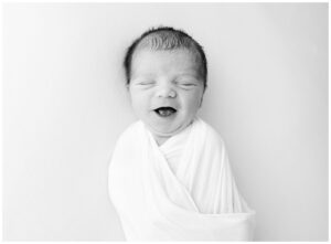 black and white photo of newborn baby boy with big smile
