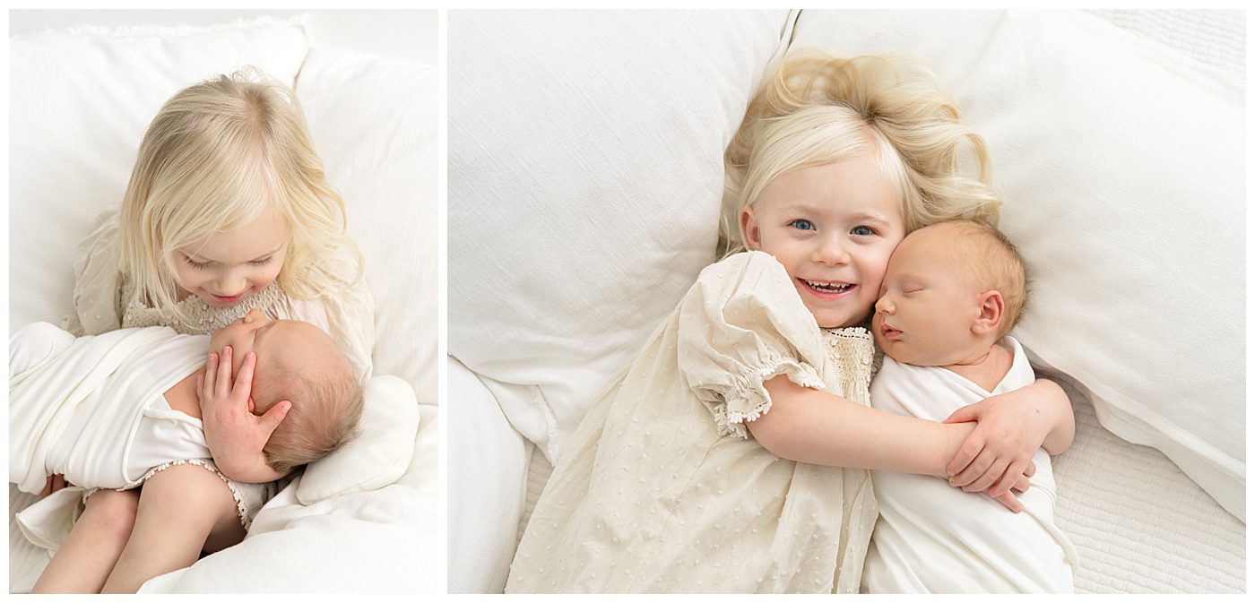 toddler girl holding her newborn baby brother on bed