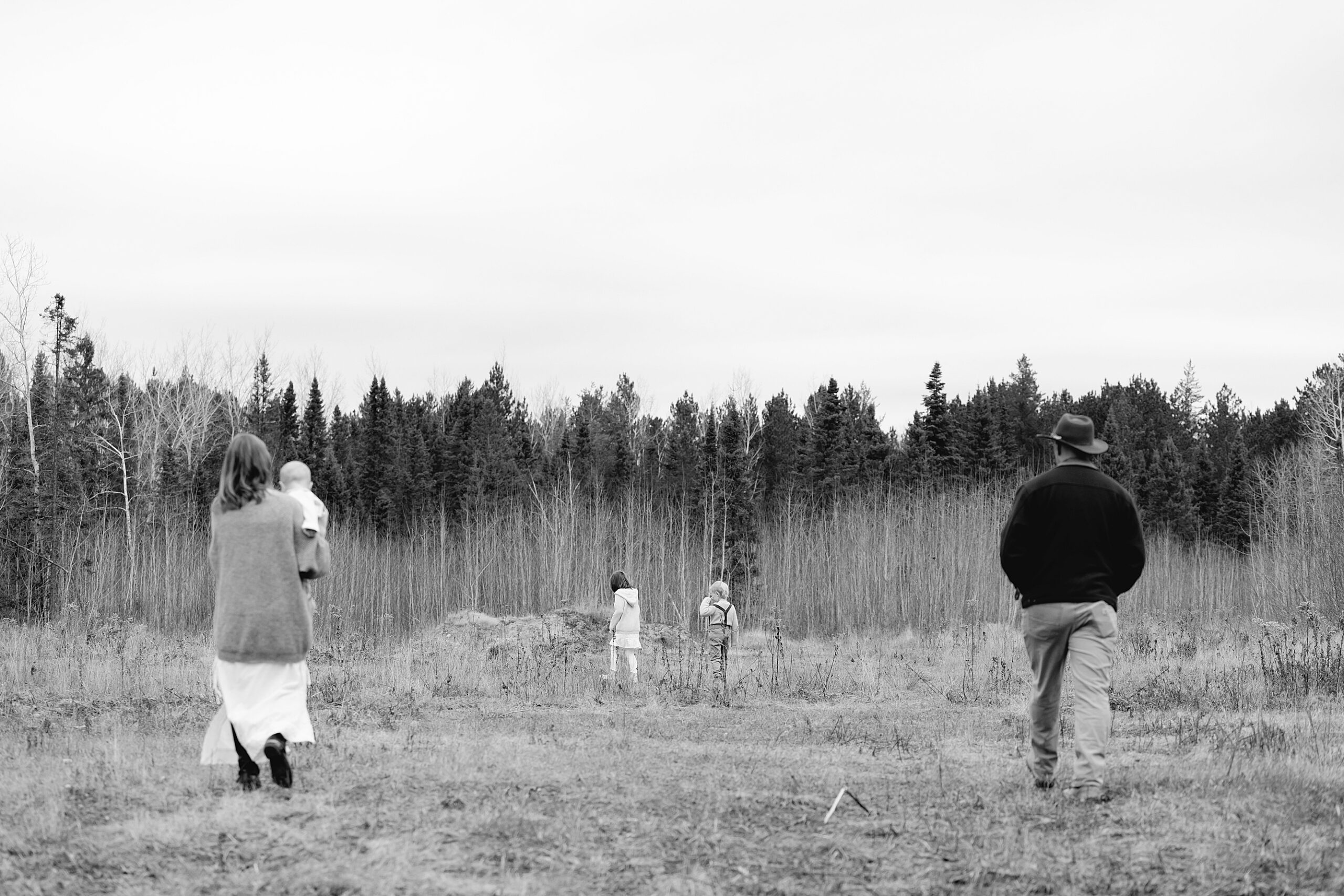 black and white photos with mom and dad on the outer edges and two older kids in the middle, all with backs turned towards camera