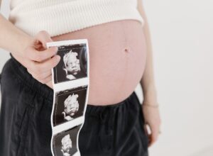 close up photo of pregnant belly and ultrasound photos