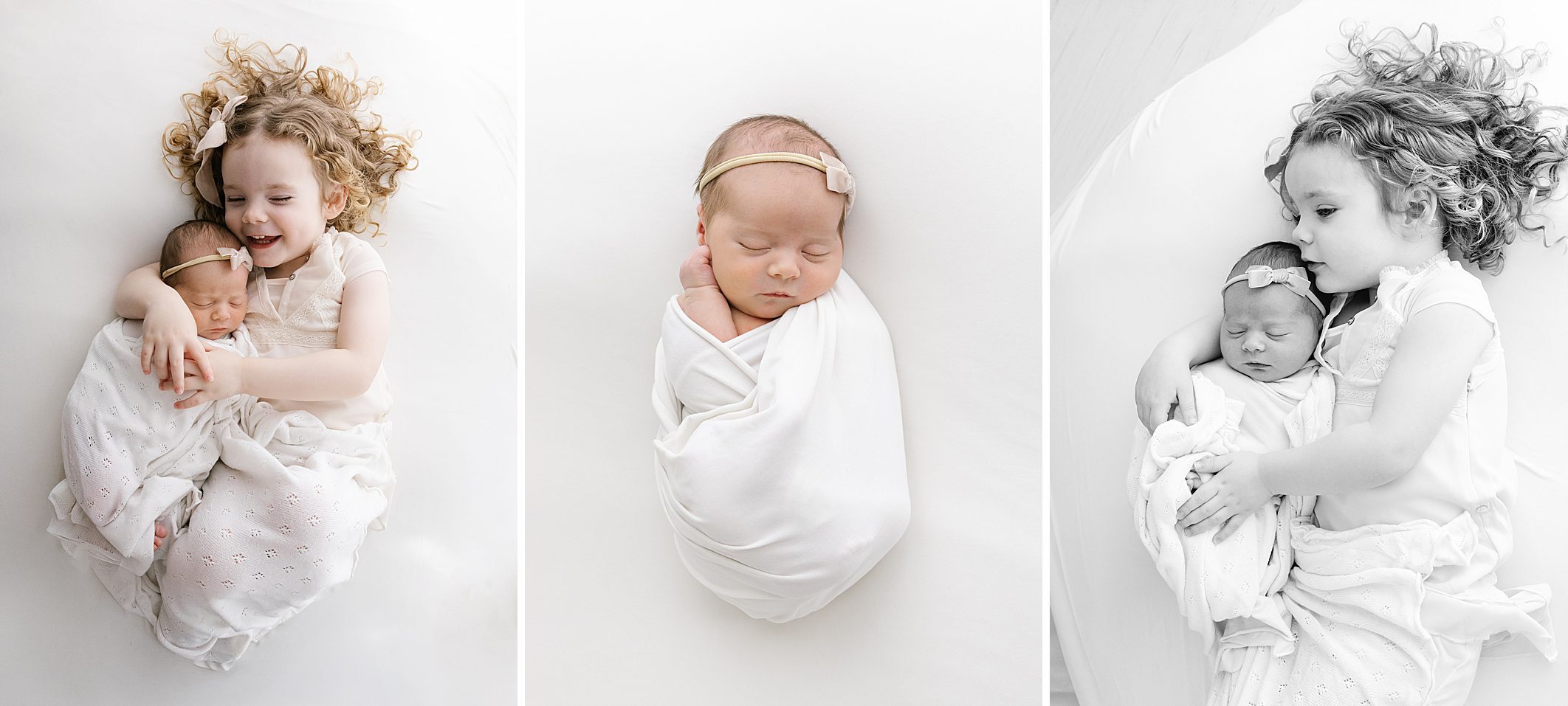 curly haired toddler sister snuggling with newborn baby girl on white blanket